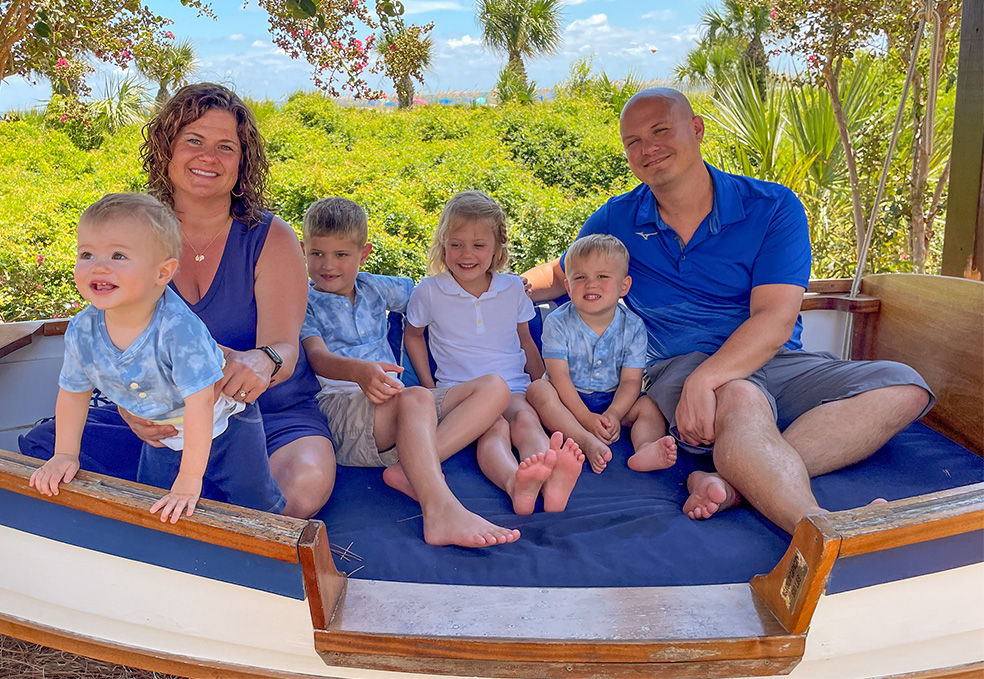 Chris and his family sitting posing in an outdoor seat